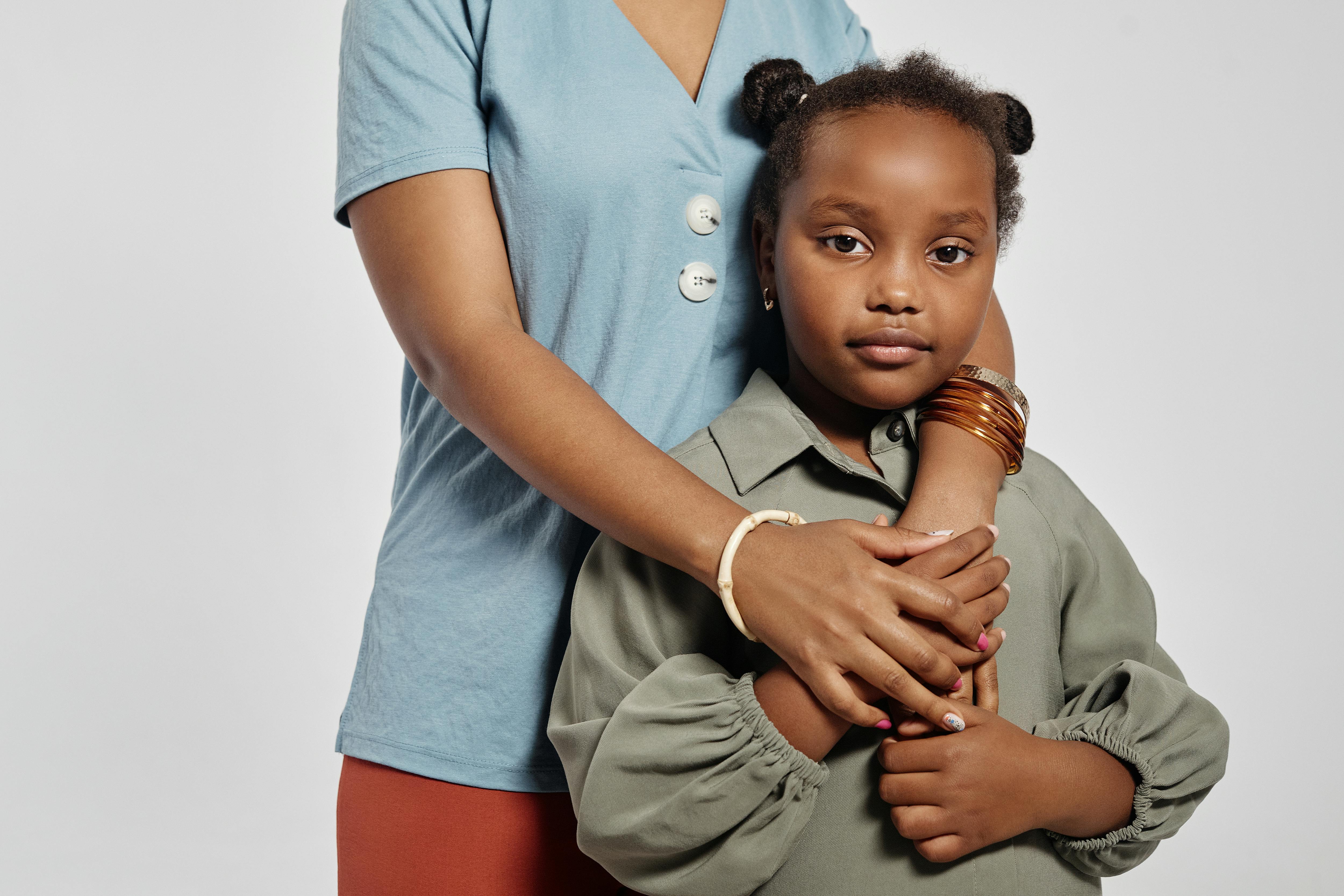 Heartwarming studio portrait of a mother embracing her daughter with love.